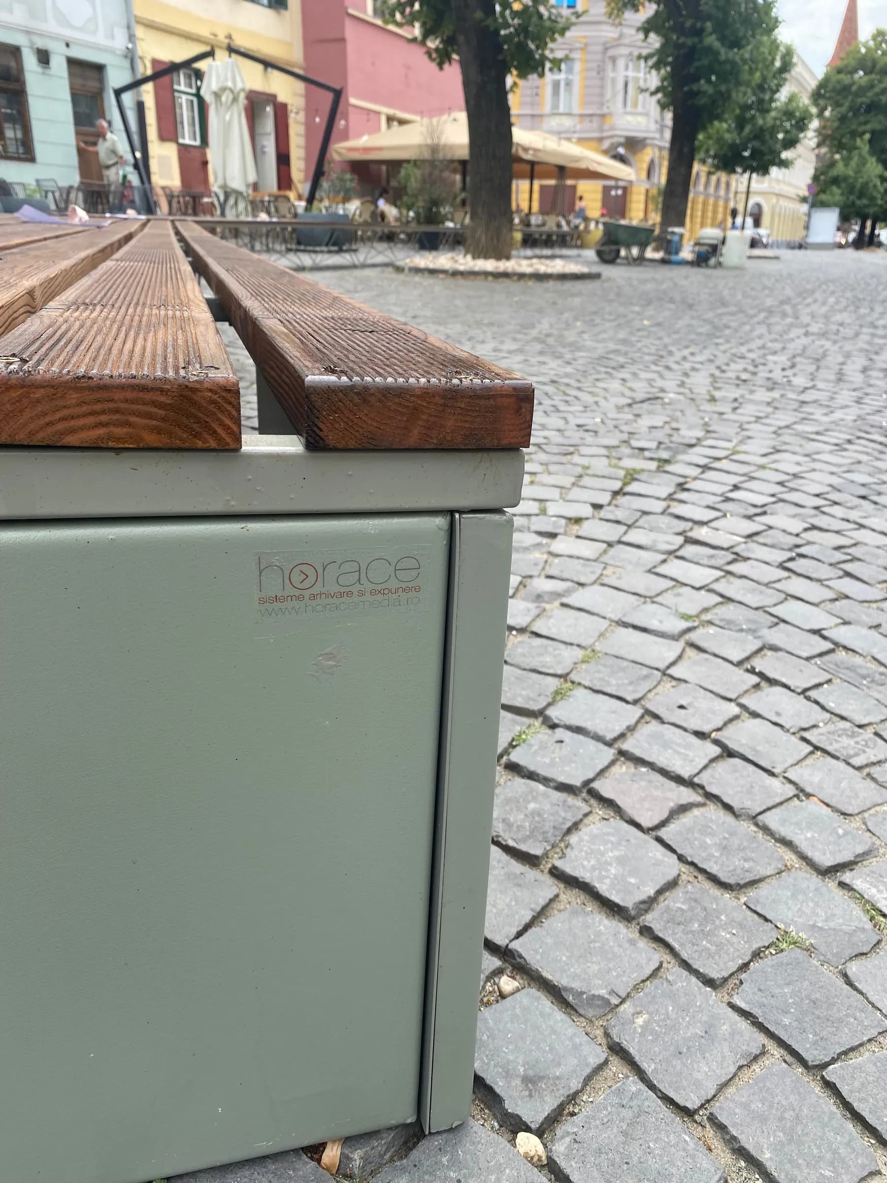 Corner of a bench: timber slats over a greenish-grey steel base, with the HORACE label