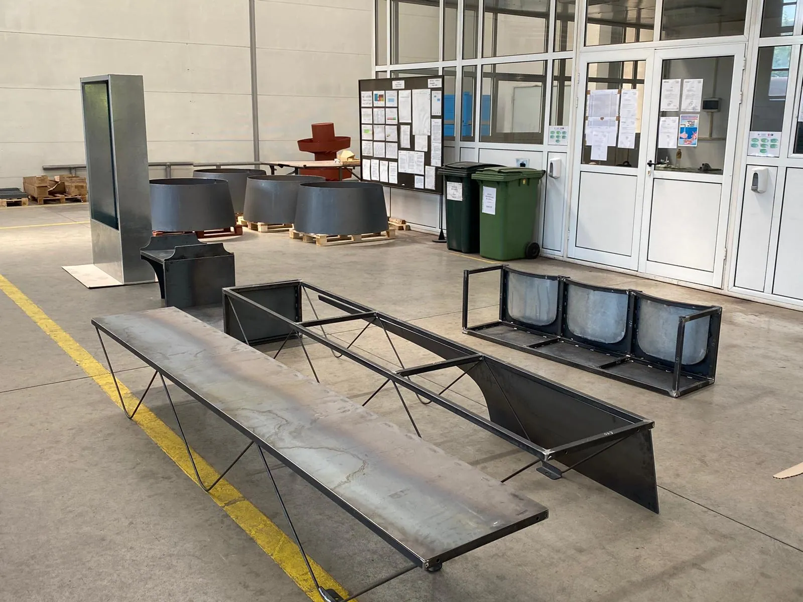 Unpainted steel bench segments laid out on the hall floor for the full-scale test