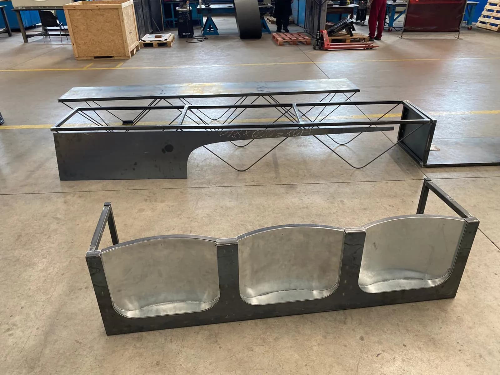 Bench frame with three curved sheet-metal seats, in front of the platform on rod legs