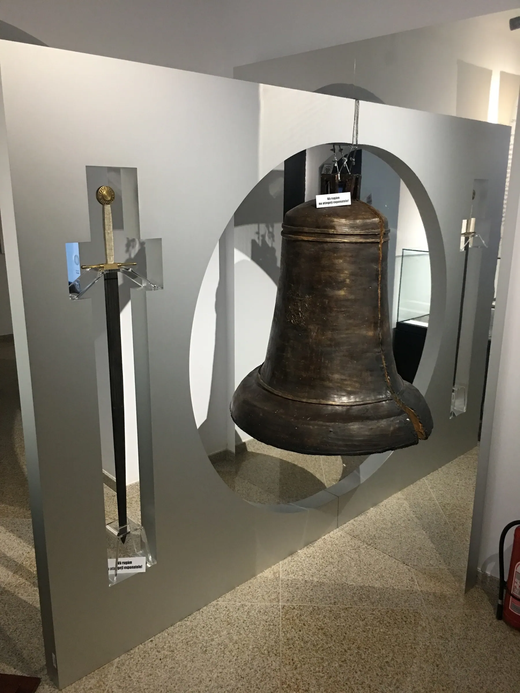 Exhibition panel with a bell and a sword set against an oval cut-out
