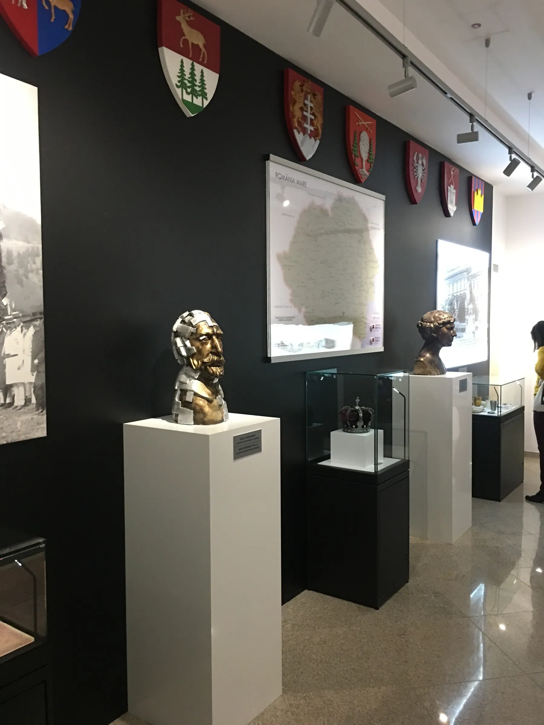 Hall with white and black plinths, busts and a black wall with coats of arms